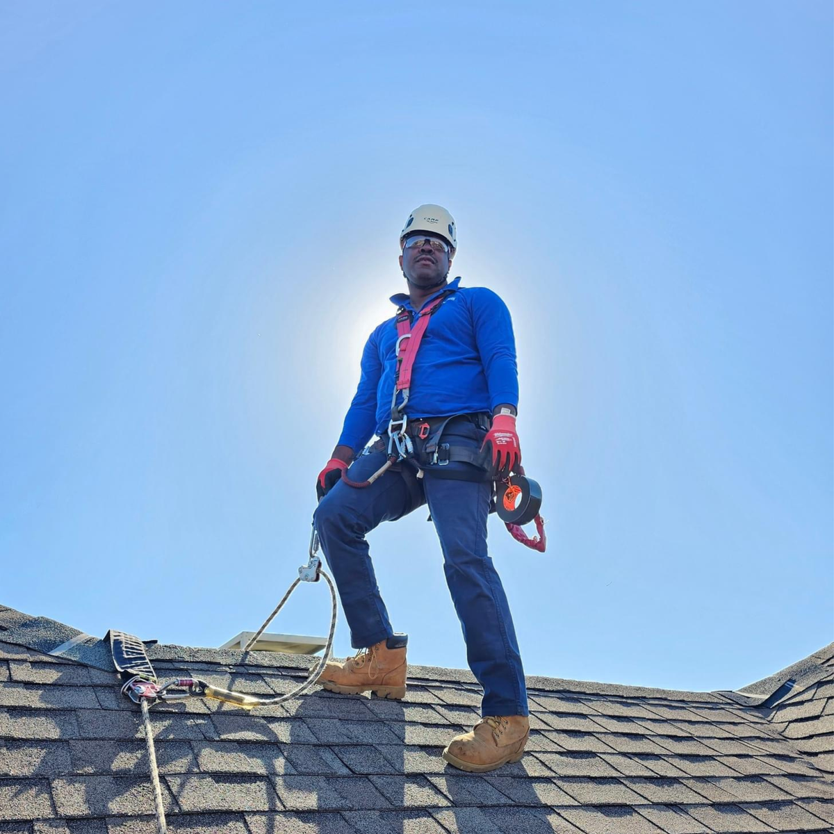 Roof worker wearing roof safety harness standing at the peak of the roof using an Eveook Fall Protection System