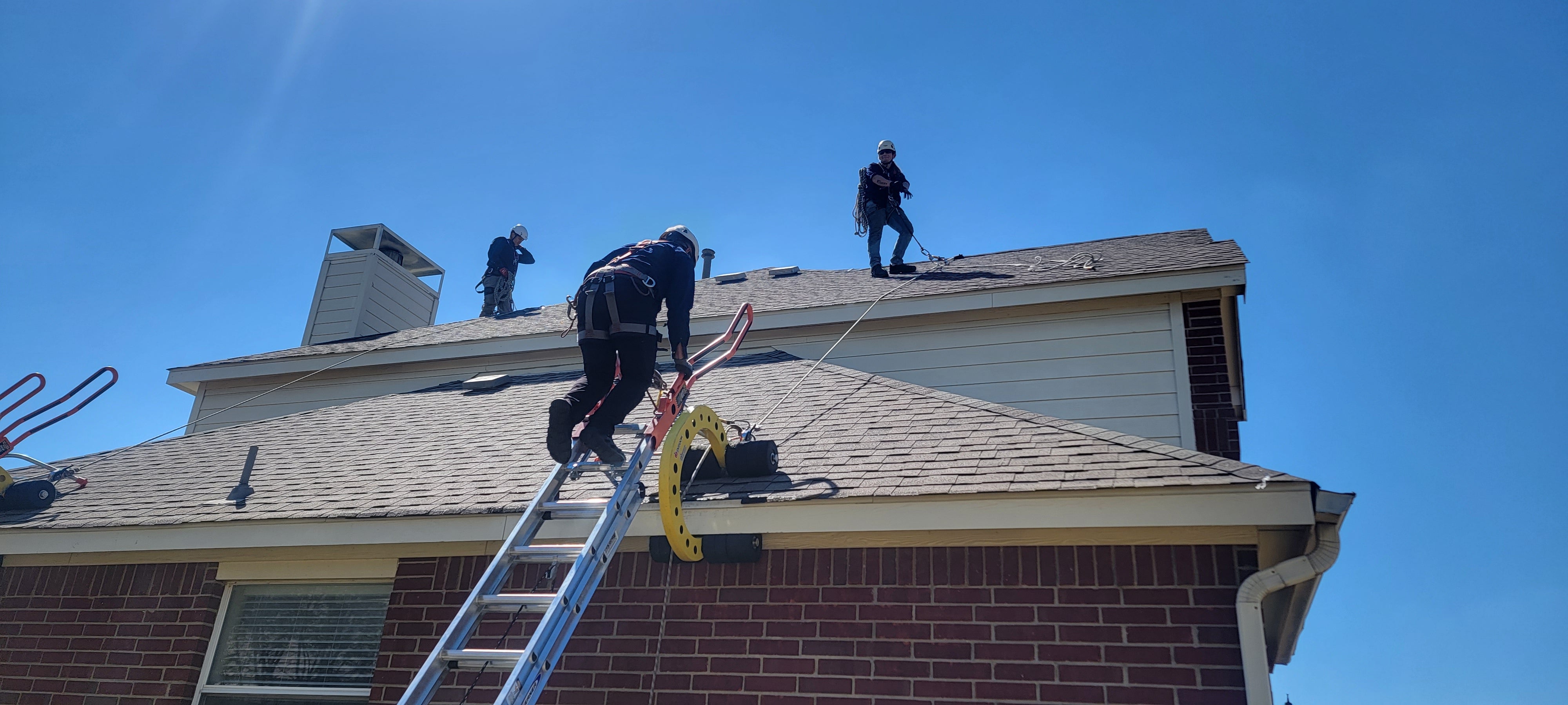 Roof worker climbing from the ladder to the roof wearing roof safety harness and using the Eveook fall protection system.