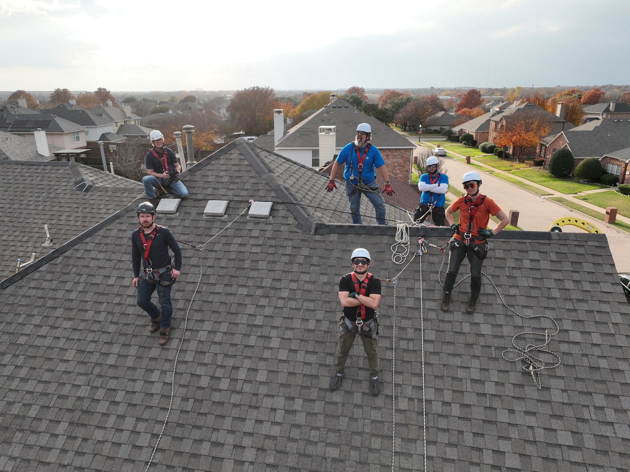 Group of roof workers using fall protection for sloped roofs using the Eveook fall protection wearing PPE, roof safety harnesses and helmets.