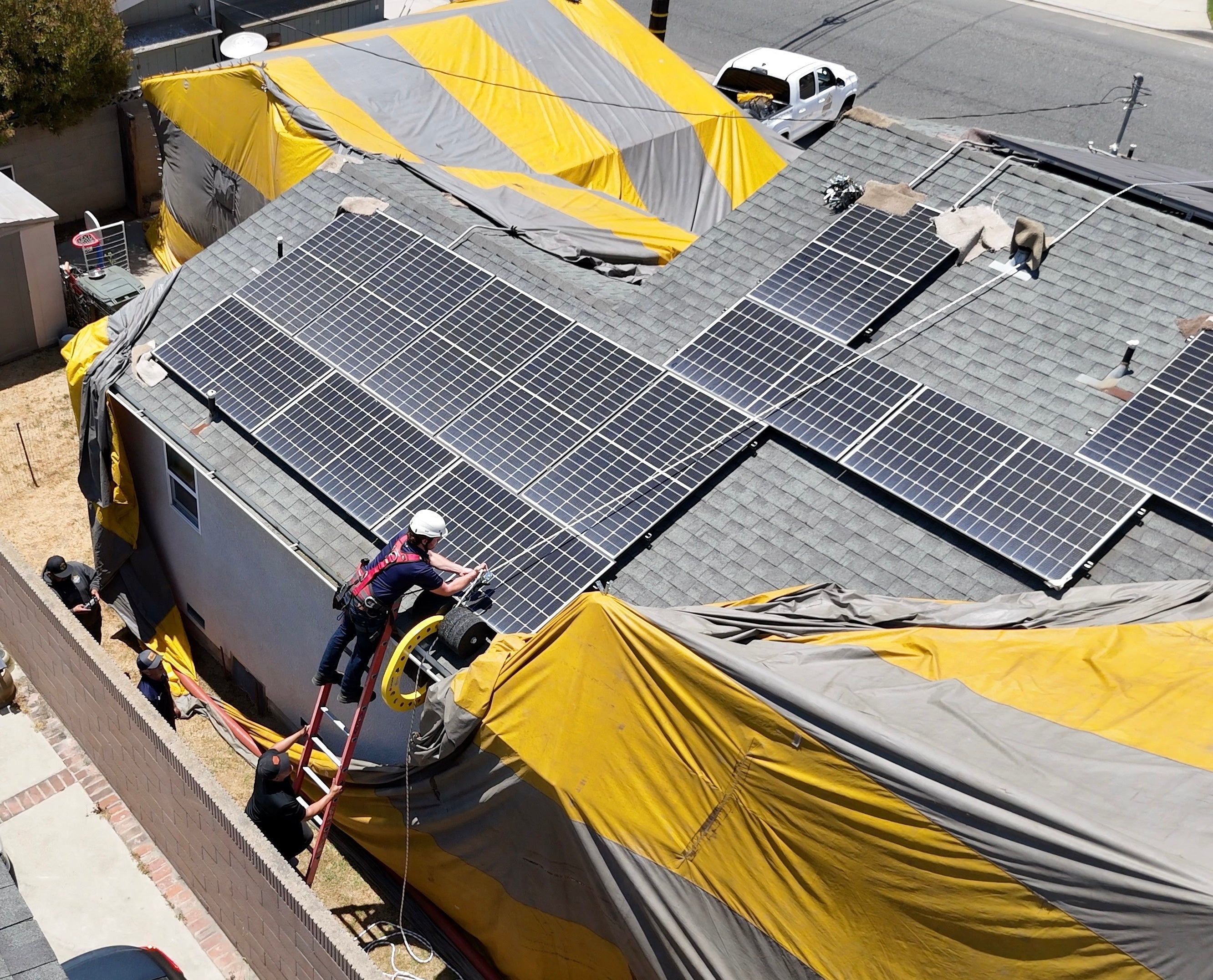 Eveook Fall Protection System for sloped roofs being installed and used on a jobsite for fumigation tent installation on a rooftop with solar panels