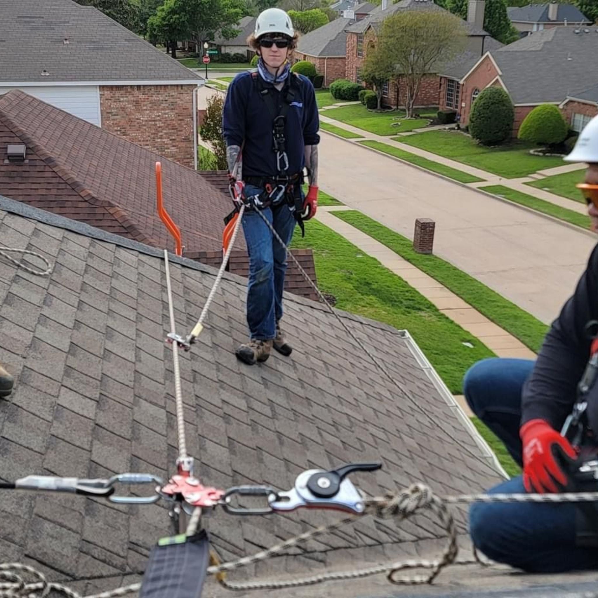 A group of roof workers on sloped roof using the Eveook Fall Protection System connected on the anchor line on the ridge of the sloped roof.