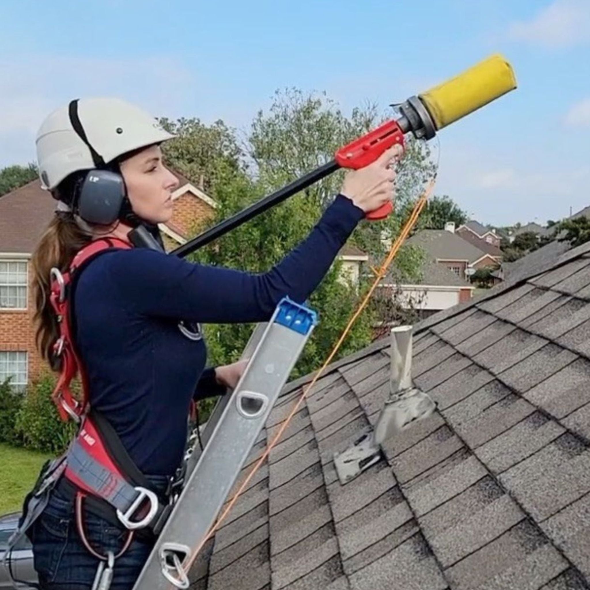 Woman sloped roof worker launching line thrower over a residential roof while on a ladder protecting the installer before they get on the roof. Eveook Fall Protection System.
