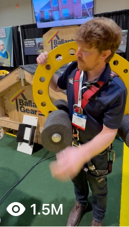 Person interacting with fall protection for residential and commercial structures at an event, with Ballantyne Gear branding visible.