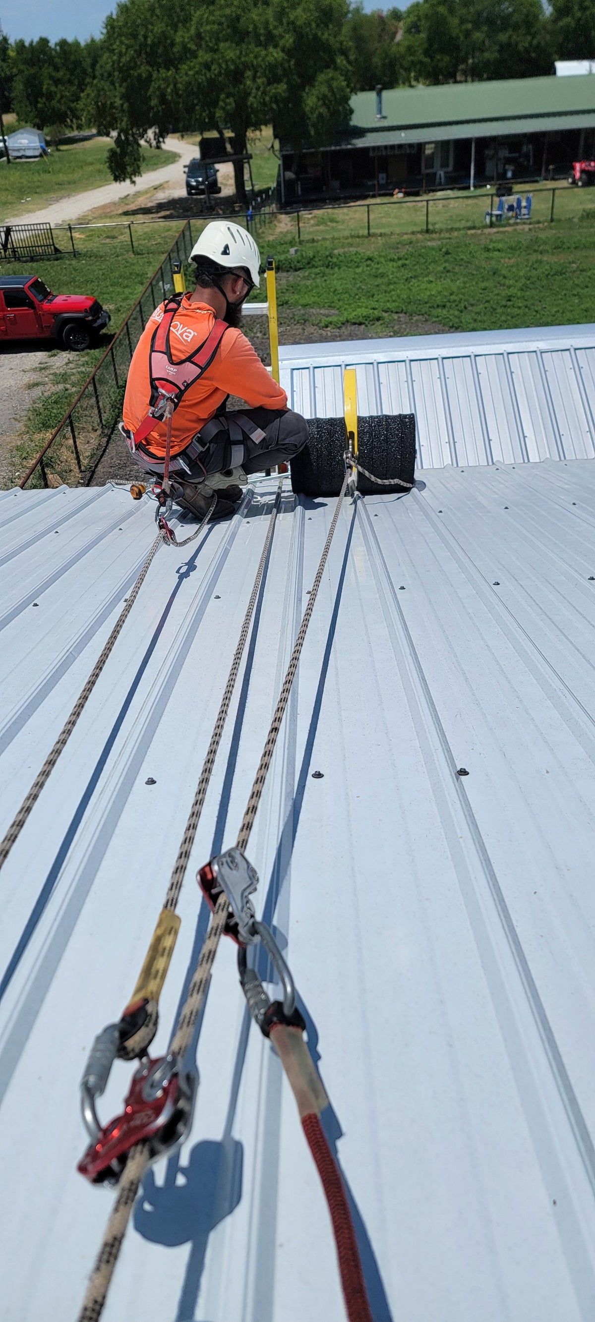 Solar Installer on metal standing seam roof using the Eveook Fall Protection System on a sloped metal roof with a CAMP Goblin  on his life line.