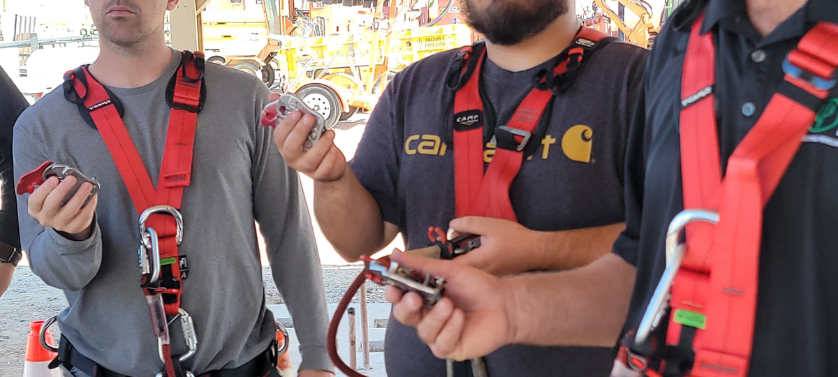 A group of  roof workers wearing a roof safety harness and PPE opening a CAMP Goblin fall arrester and rope grab with one hand
