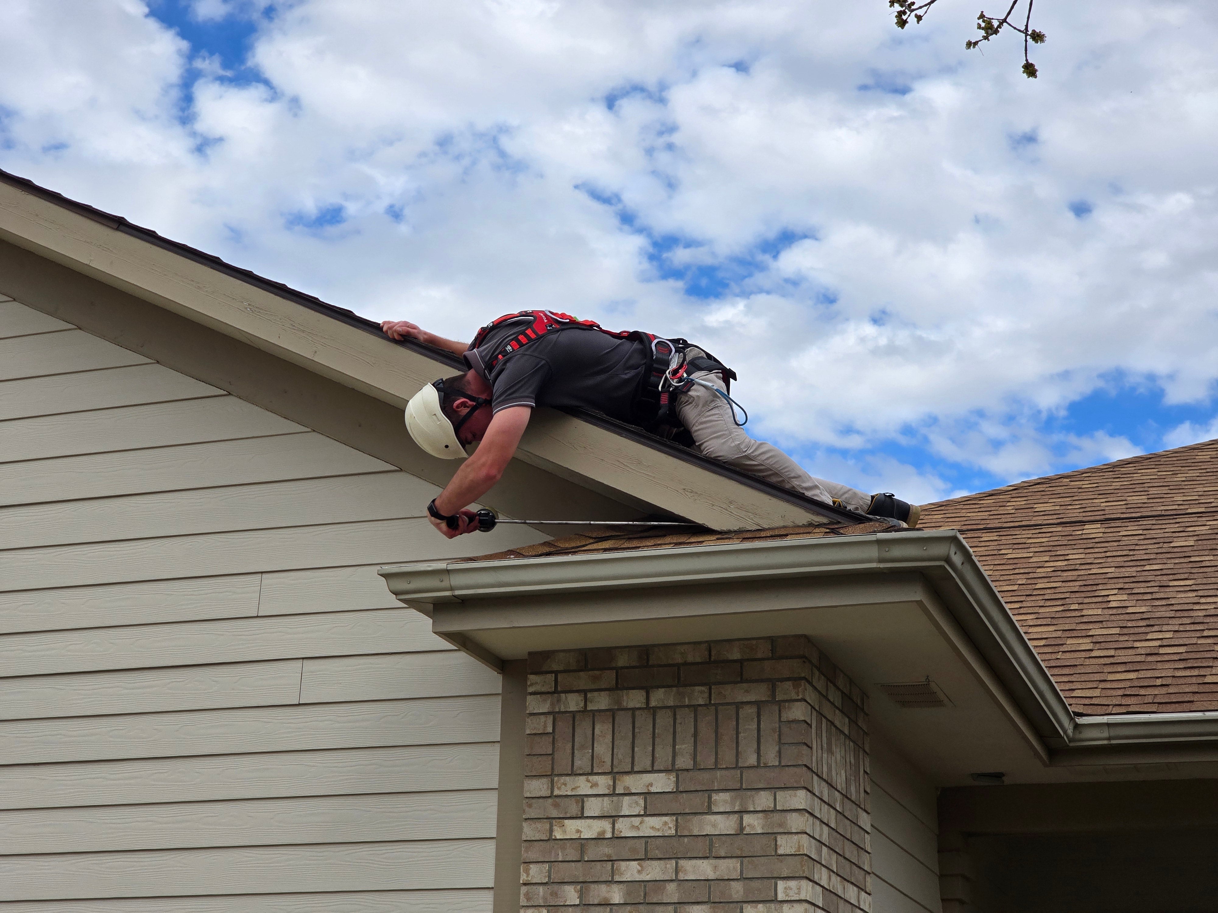Pest control service using Eveook Fall Protection System leaning over the edge to look for rodent exclusions and complete wildlife and rodent service. 