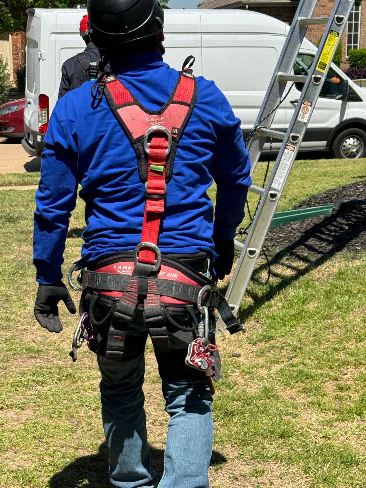 Roof safety harness worn by worker walking towards a ladder using fall protection at a residential roofing project