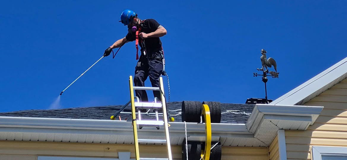 Roof worker spraying roof protectant chemical on a roof using Eveook Fall Protection System