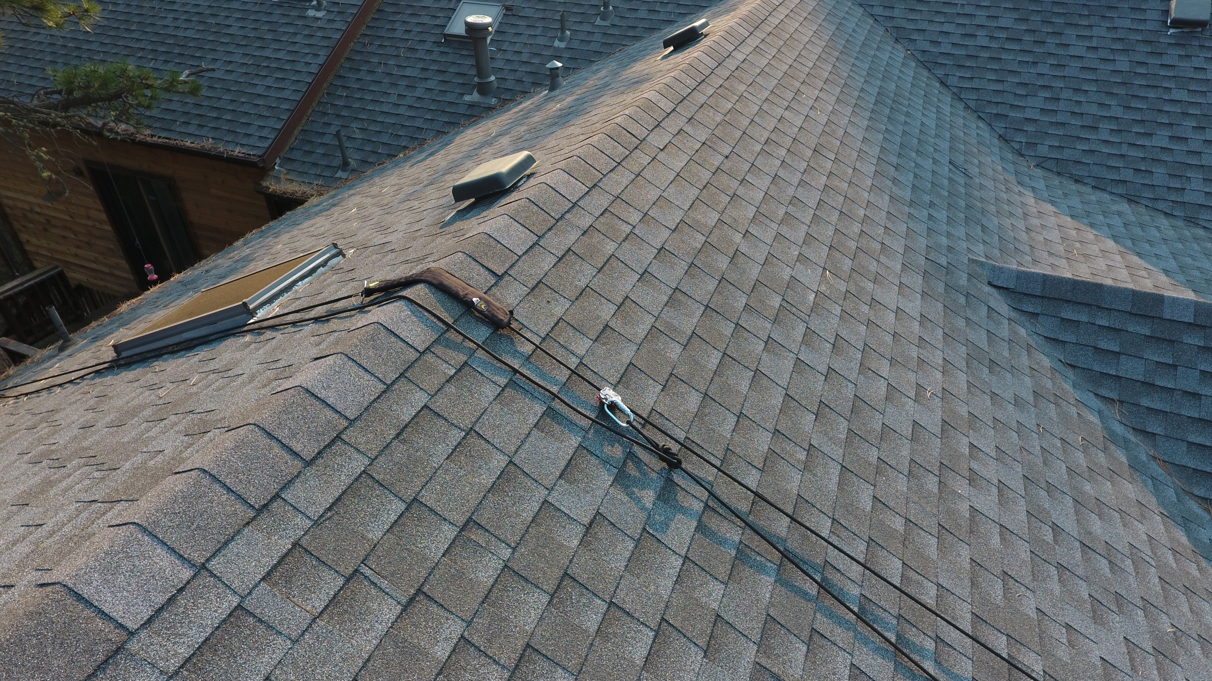 Roof with shingles and tools on a residential property. The rope protector is protecting the shingles at the ridge. 